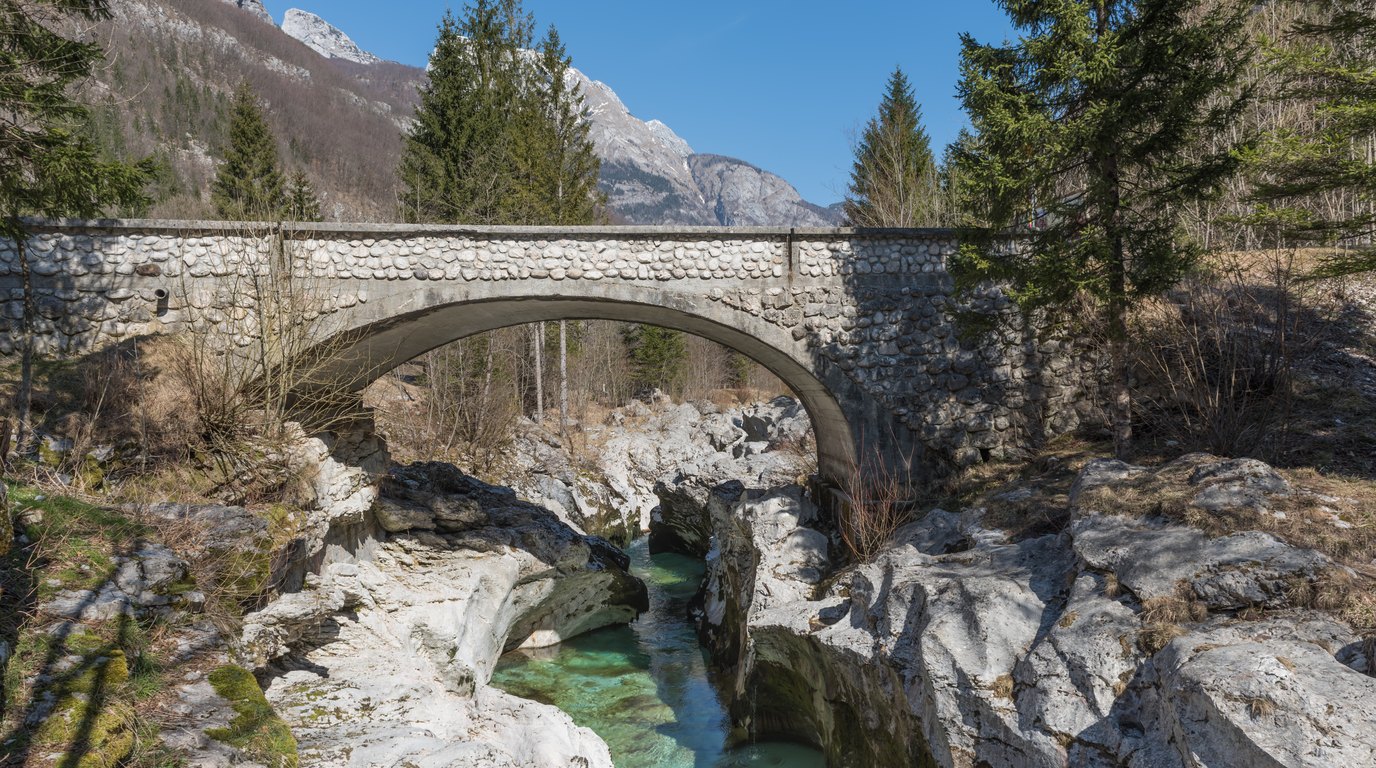 The emerald green Soča river flowing through a narrow limestone gorge below the wooded slopes of the Julian Alps