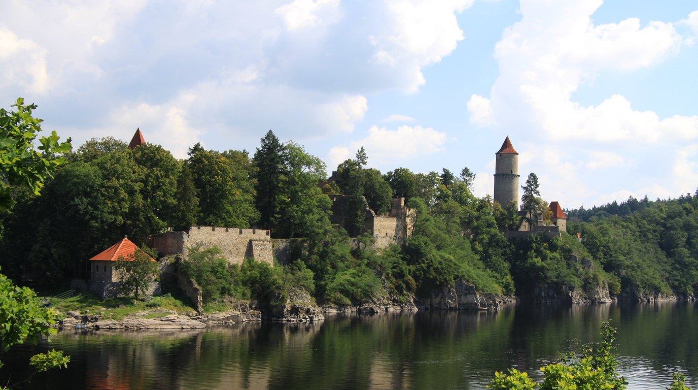 A castle on a rocky promontory above the water of a reservoir in the Central Vltava region
